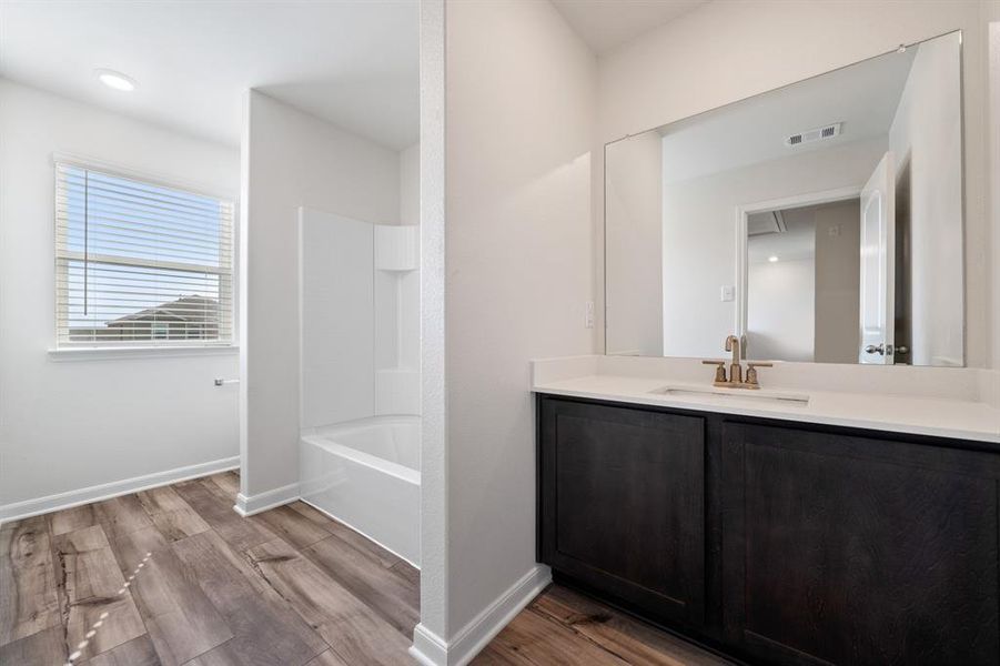 Bathroom with hardwood / wood-style flooring, shower / tub combination, and vanity