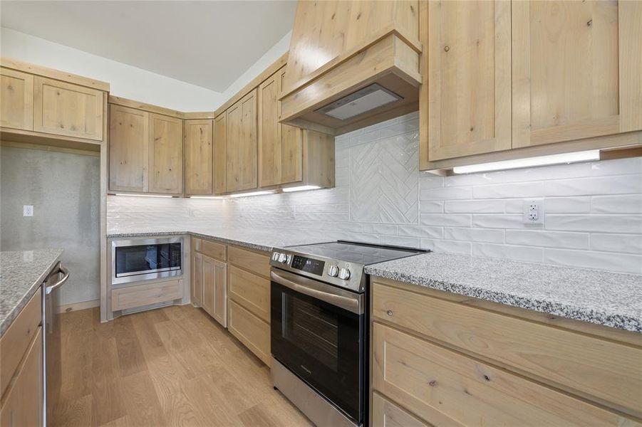 Kitchen with stainless steel appliances, light stone countertops, light wood finish cabinets, and light wood finished floors Kitchen with stainless steel appliances, light stone countertops, light wood finish cabinets, and light wood finished floors