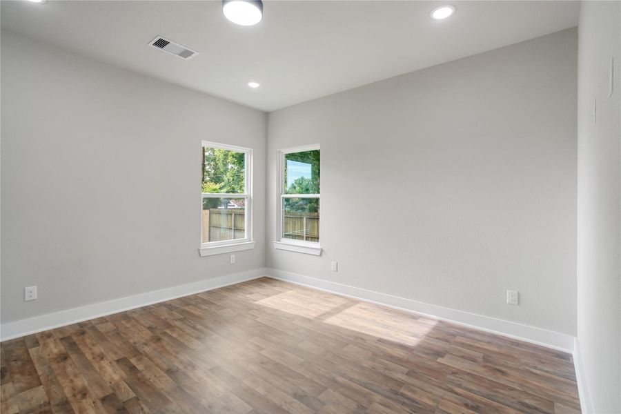 This room features fresh paint, wood flooring, and ample natural light from two windows. The recessed lighting and neutral walls offer a modern, clean look, perfect for personalization. This room features fresh paint, wood flooring, and ample natural light from two windows. The recessed lighting and neutral walls offer a modern, clean look, perfect for personalization.