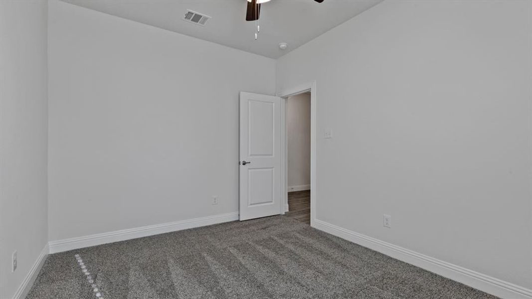 Carpeted spare room with a ceiling fan and baseboards