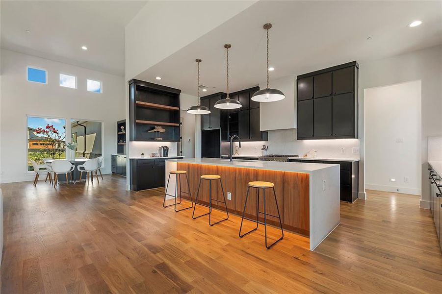 Gourmet kitchen featuring a large central island with integrated lighting, dark cabinetry, and light countertops Gourmet kitchen featuring a large central island with integrated lighting, dark cabinetry, and light countertops