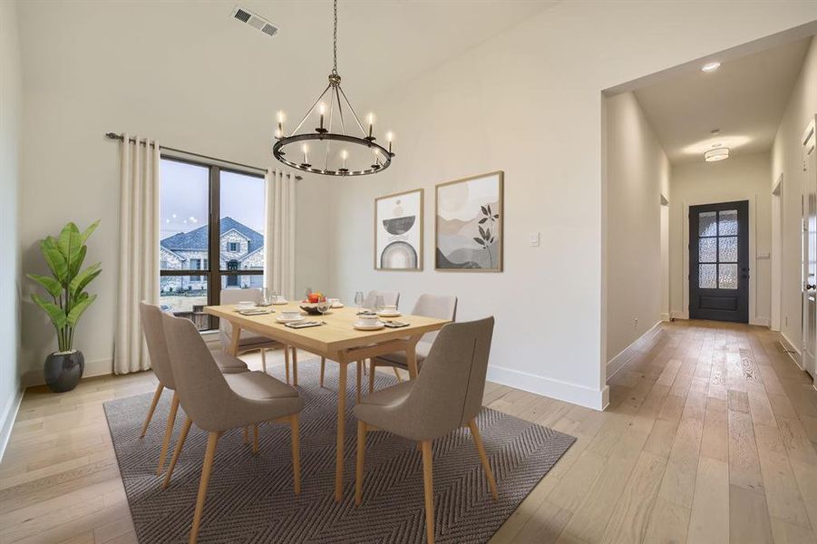Virtually Staged - Dining space featuring light wood-style flooring, a chandelier, and a high ceiling
