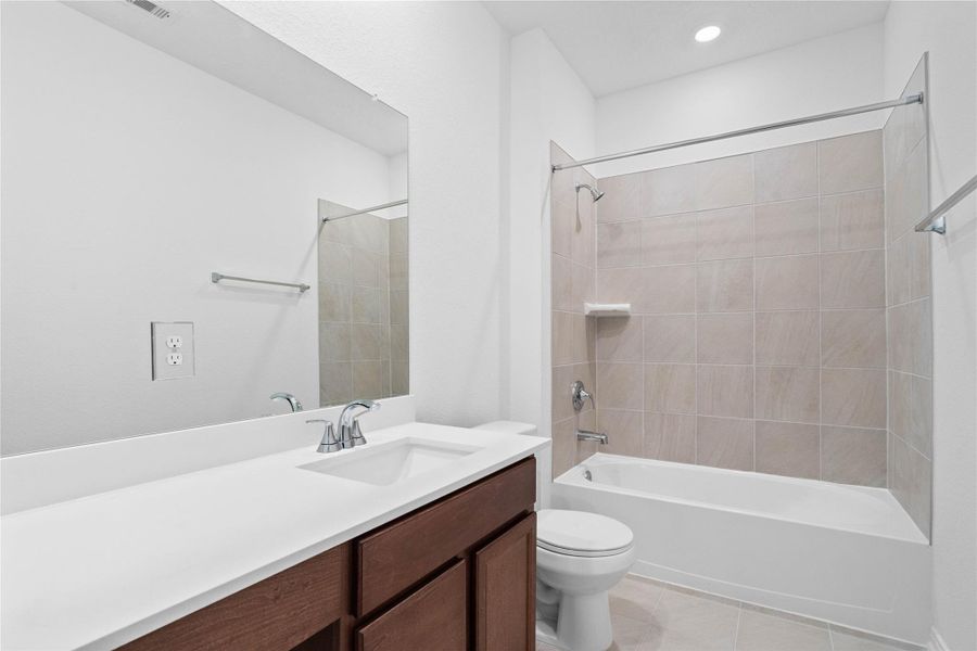 The secondary bathroom showcases tile flooring, a bath/shower combo with a Daltile tile surround, a vanity with knee space and a stunning light countertop, a mirror, sleek fixtures, and contemporary finishes throughout. The secondary bathroom showcases tile flooring, a bath/shower combo with a Daltile tile surround, a vanity with knee space and a stunning light countertop, a mirror, sleek fixtures, and contemporary finishes throughout.