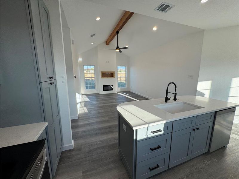 Kitchen with ceiling fan, sink, dark hardwood / wood-style flooring, lofted ceiling with beams, and stainless steel dishwasher