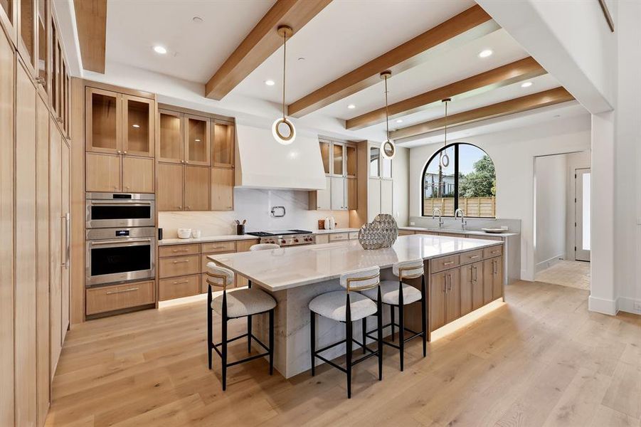 The chef’s kitchen is a masterpiece, featuring a Wolf steam oven, a built-in Miele coffee maker, Bianco Superiore Quartzite countertops, a 48-inch range, and SubZero refrigerator and freezer units