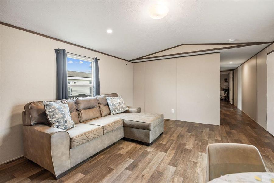 Open living area featuring wood-finish flooring, neutral-toned walls, and a recessed ceiling light Open living area featuring wood-finish flooring, neutral-toned walls, and a recessed ceiling light