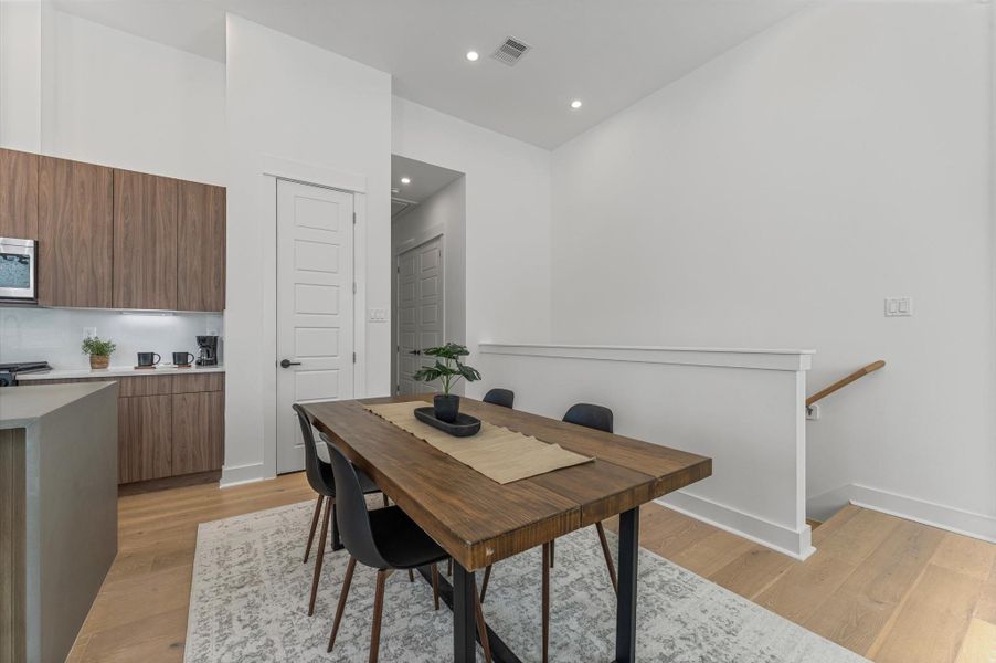 The dining area, part of the open-concept living, dining, and kitchen on the second floor, offers ample space for a large table, making it perfect for family meals or entertaining friends, while seamlessly flowing with the bright, airy atmosphere of the surrounding living space.