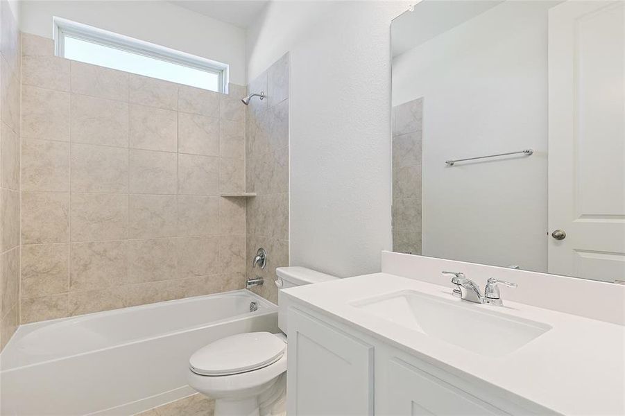 Full bathroom featuring tiled shower / bath, vanity, and toilet