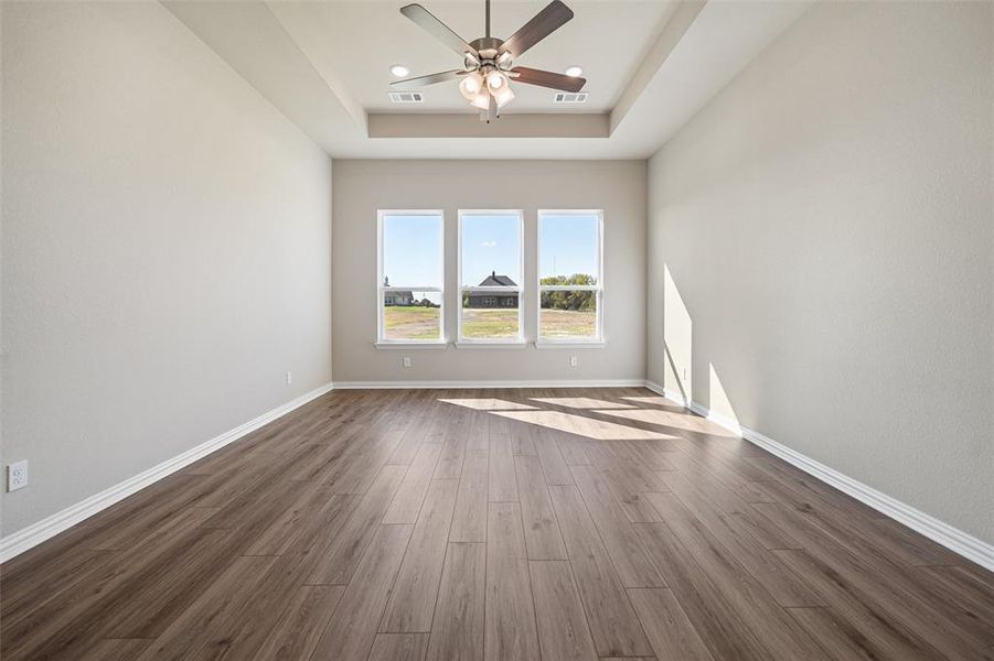 Spare room featuring dark wood-type flooring, a ceiling fan, and a raised ceiling
