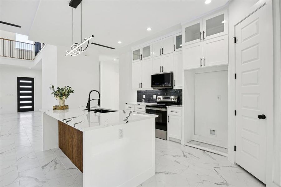 Kitchen featuring glass insert cabinets, electric stove, recessed lighting, pendant lighting, and light stone countertops
