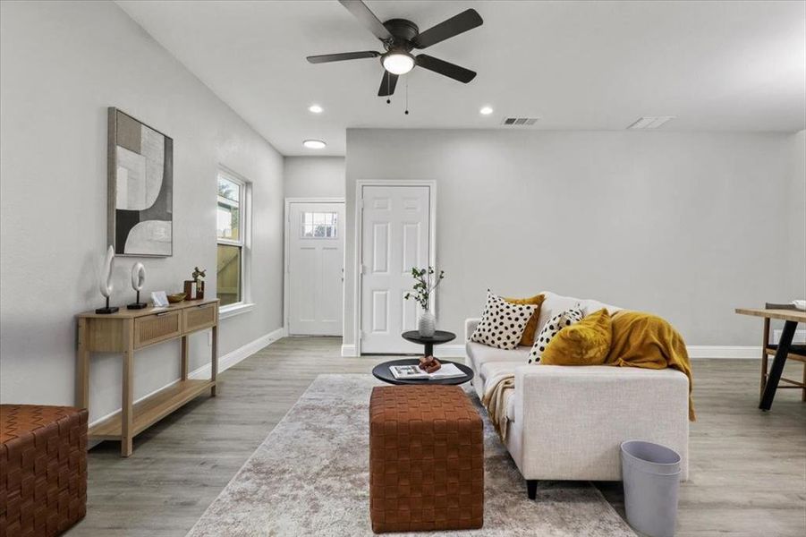 Living room with ceiling fan and hardwood / wood-style flooring