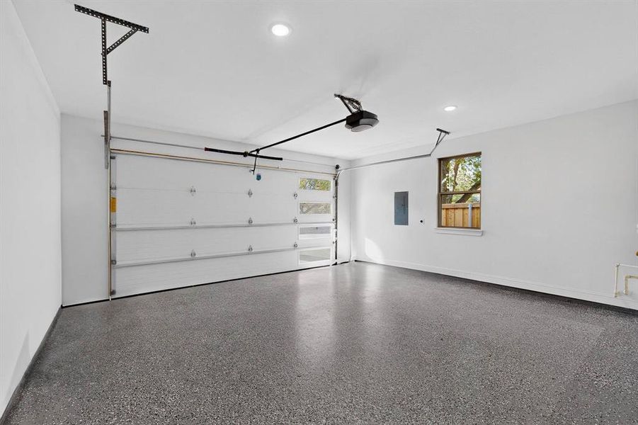 Garage with recessed lighting, electric panel, and a garage door opener