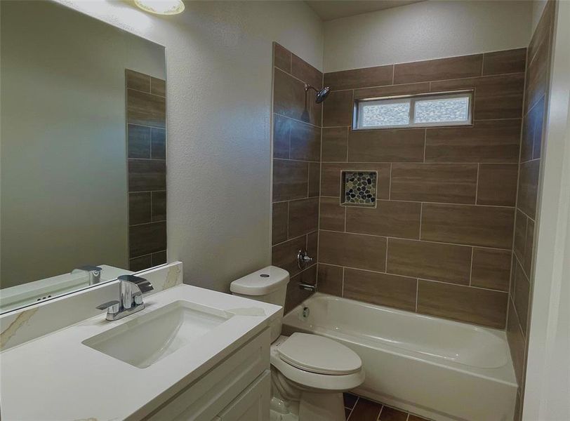 Full bathroom with tiled shower / bath, vanity, and toilet