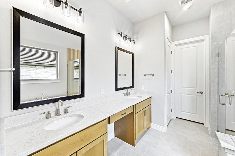 Dual vanity featuring light wood-finish cabinetry, white stone-finish countertops, and under-mount sinks with brushed nickel fixtures