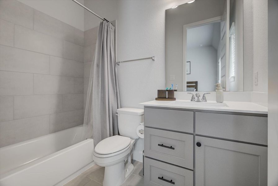 This private ensuite bathroom includes a well-designed tub-and-shower combo, soft-close cabinetry for refined storage, and exceptional lighting that enhances the space.