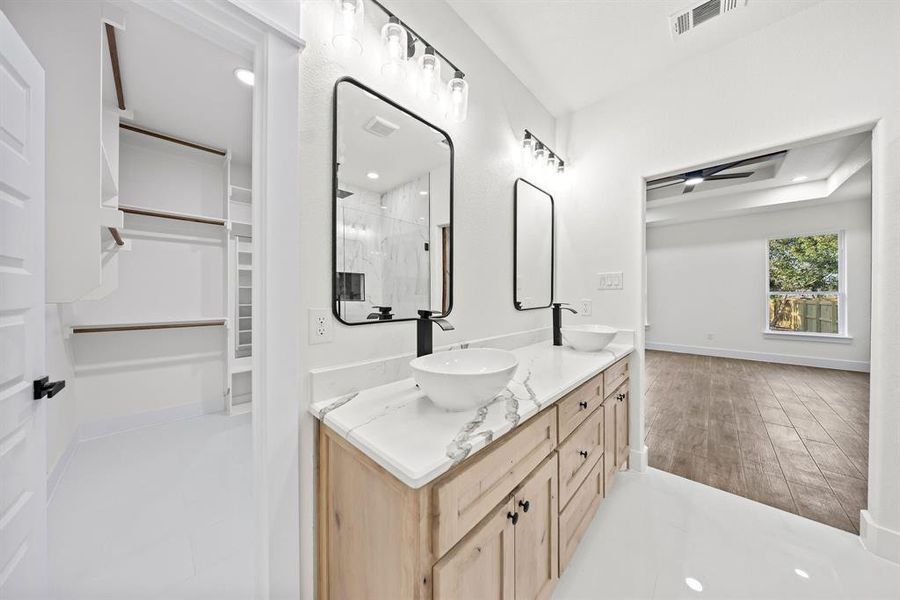 Bathroom with a spacious closet, double vanity, and a shower