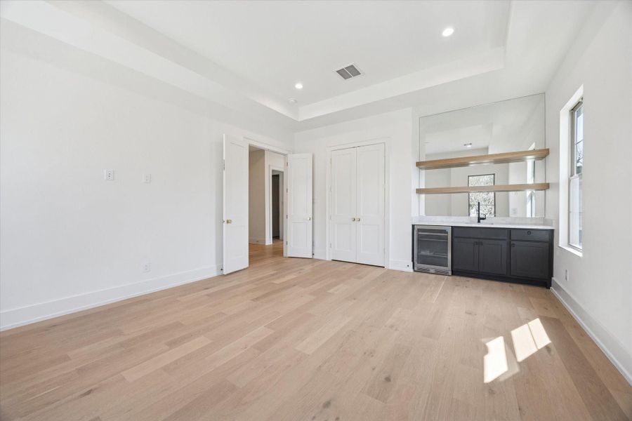 Upstairs game room complete with built-in cabinetry, a beverage refrigerator, custom shelving, a tray ceiling, and recessed lighting.
