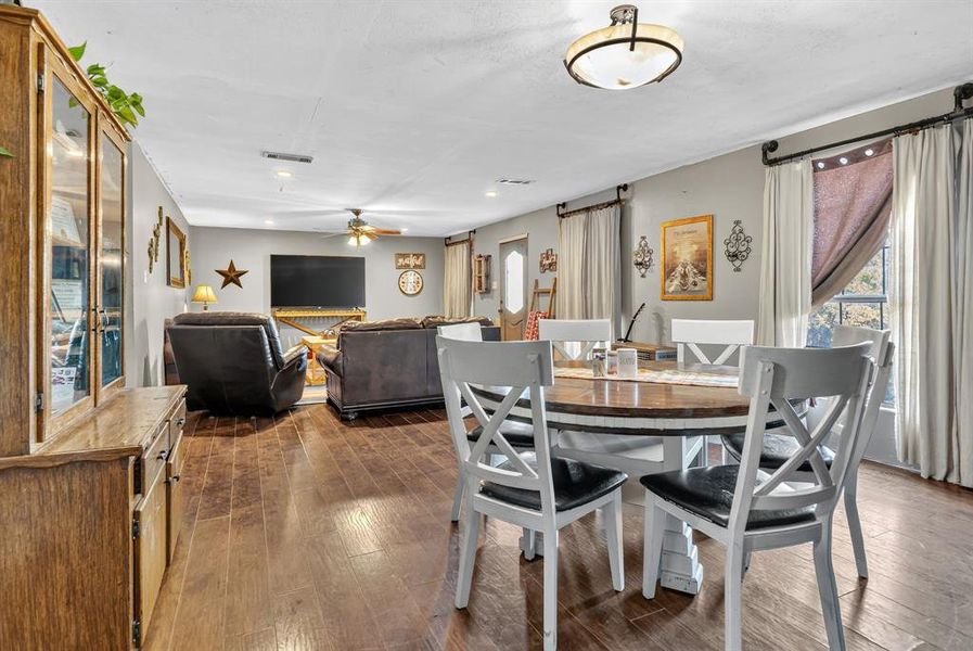 Dining room featuring dark wood-style flooring, a ceiling fan, and a barn door Dining room featuring dark wood-style flooring, a ceiling fan, and a barn door