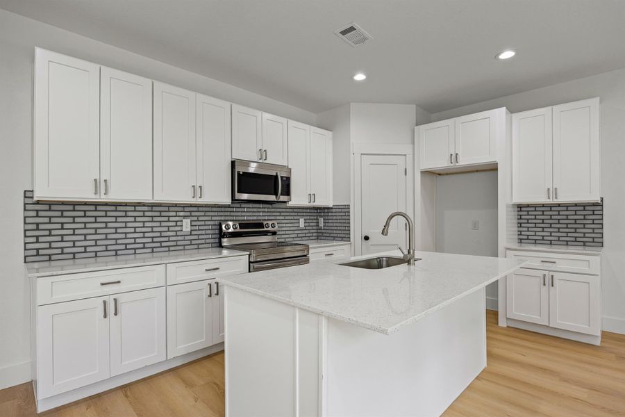 Kitchen with appliances with stainless steel finishes, white cabinetry, decorative backsplash, recessed lighting, and light stone counters Kitchen with appliances with stainless steel finishes, white cabinetry, decorative backsplash, recessed lighting, and light stone counters
