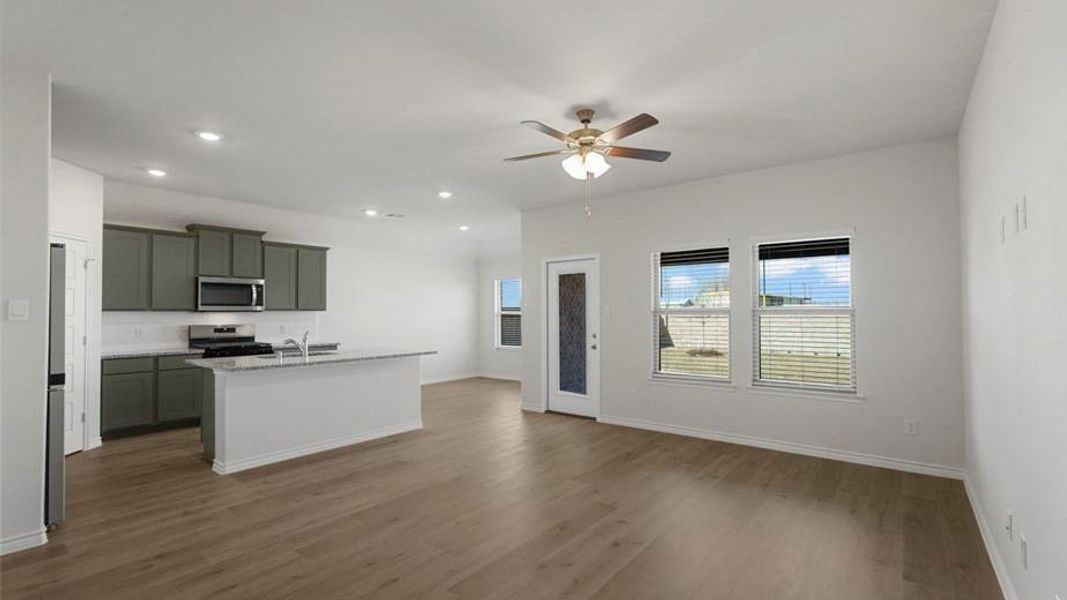 Open-concept living area featuring wood-finish flooring, a contemporary ceiling fan, and recessed lighting