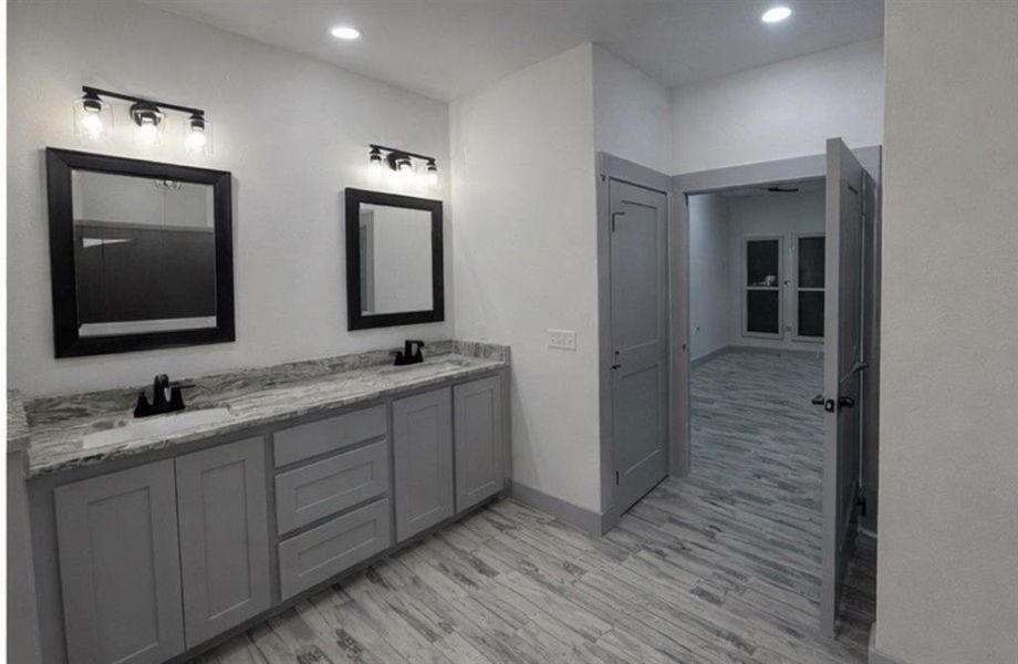 Bathroom featuring double vanity, light wood-style floors, and recessed lighting