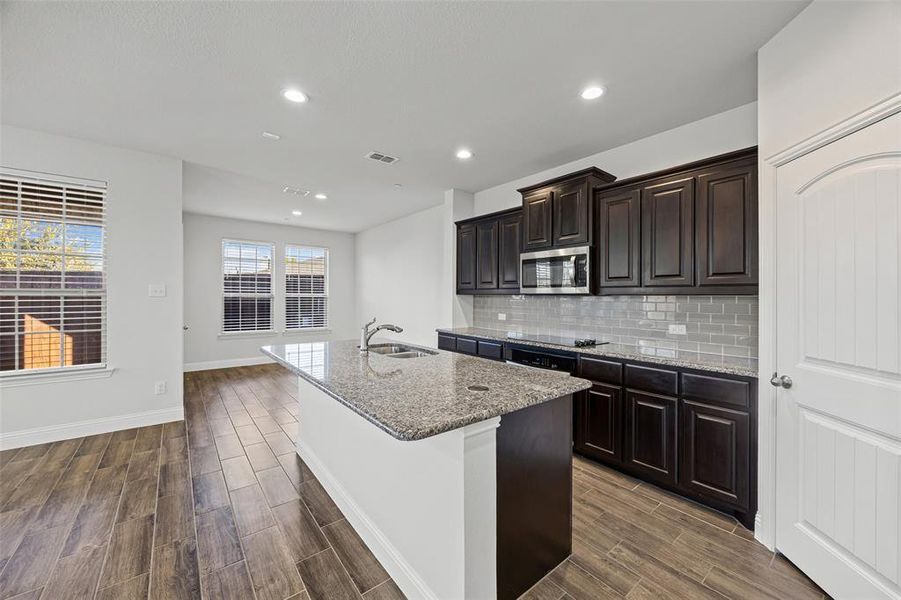 Large kitchen with granite counters and stainless appliances.