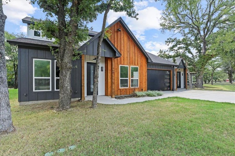 Contemporary home featuring board and batten siding, a front lawn, and driveway