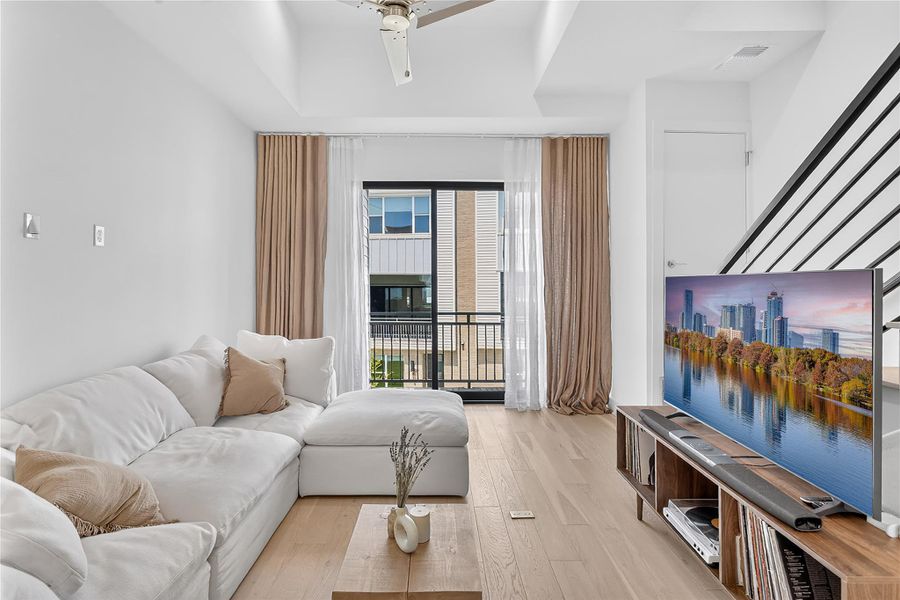 A living space with light wood flooring and a modern balcony provides an inviting, comfortable atmosphere.