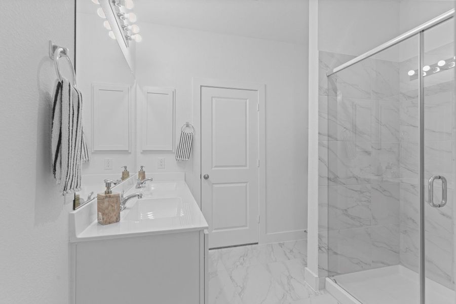 The elegant primary bathroom offers dual sinks, sleek quartz countertops, and bright lighting that makes the space feel fresh and welcoming. Every detail is designed for both beauty and function, giving this suite a touch of spa-like comfort. **Image Representative of Plan Only and May Vary as Built**.