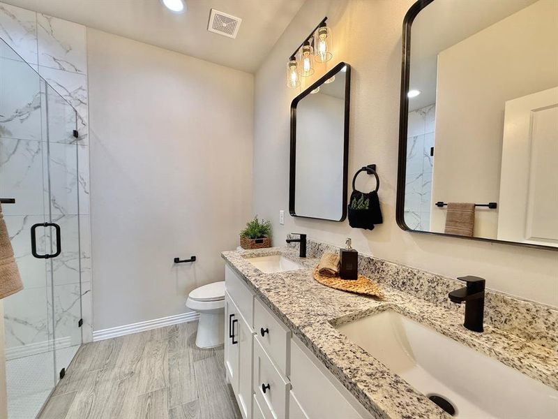 Bathroom featuring hardwood / wood-style flooring, toilet, vanity, and a shower with shower door