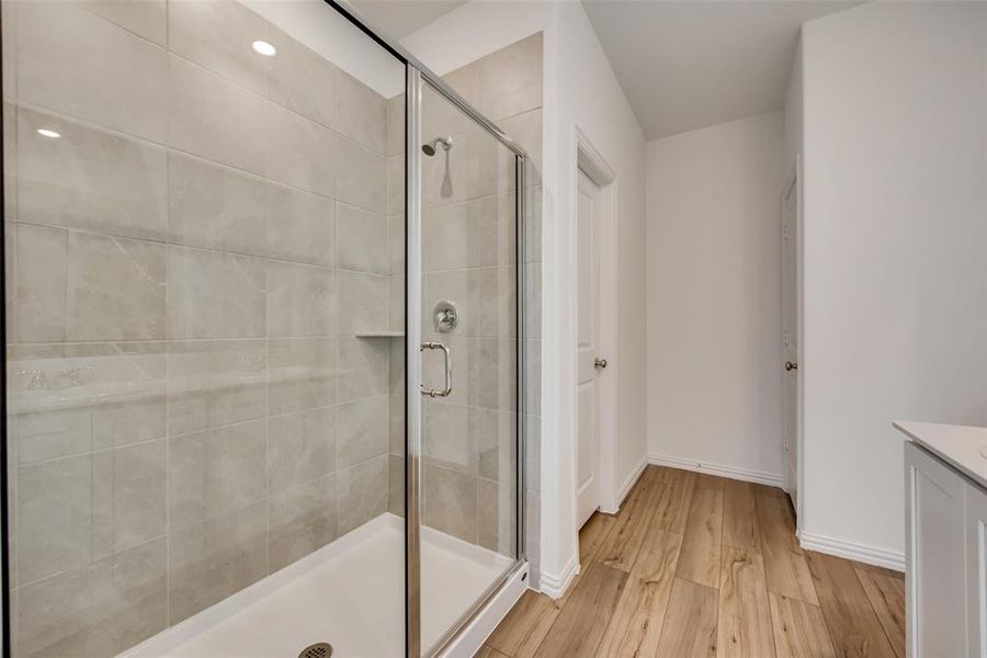 Bathroom featuring vanity, hardwood / wood-style flooring, and a shower with door