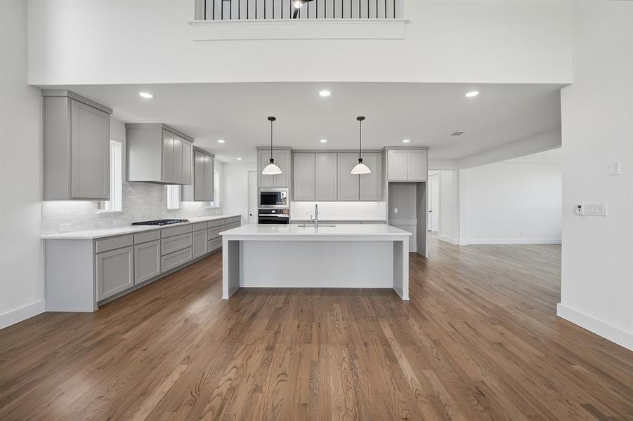 Kitchen featuring a center island with sink, pendant lighting, light stone counters, light wood-style flooring, and recessed lighting Kitchen featuring a center island with sink, pendant lighting, light stone counters, light wood-style flooring, and recessed lighting