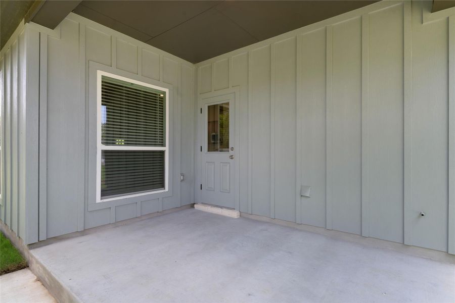 Property entrance featuring board and batten siding and a patio