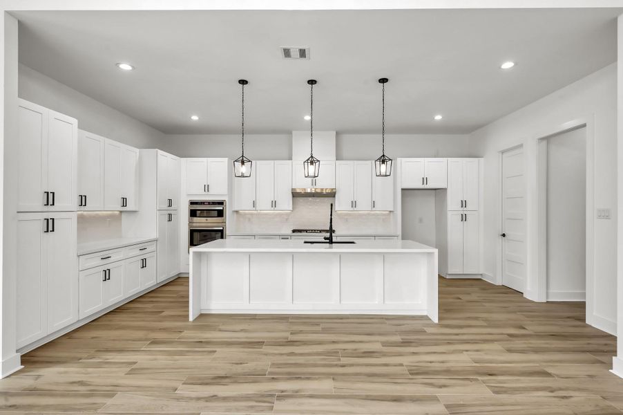 Chef’s kitchen with sleek quartz countertops, custom cabinetry, built-in stainless appliances, and a spacious island with seating and prep sink.
