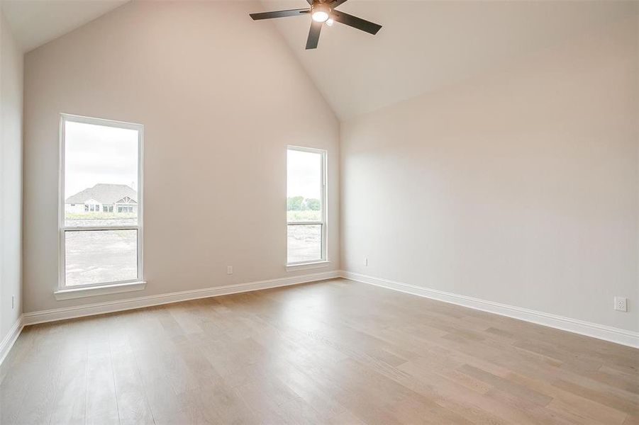 Empty room featuring high vaulted ceiling, light hardwood / wood-style floors, and ceiling fan