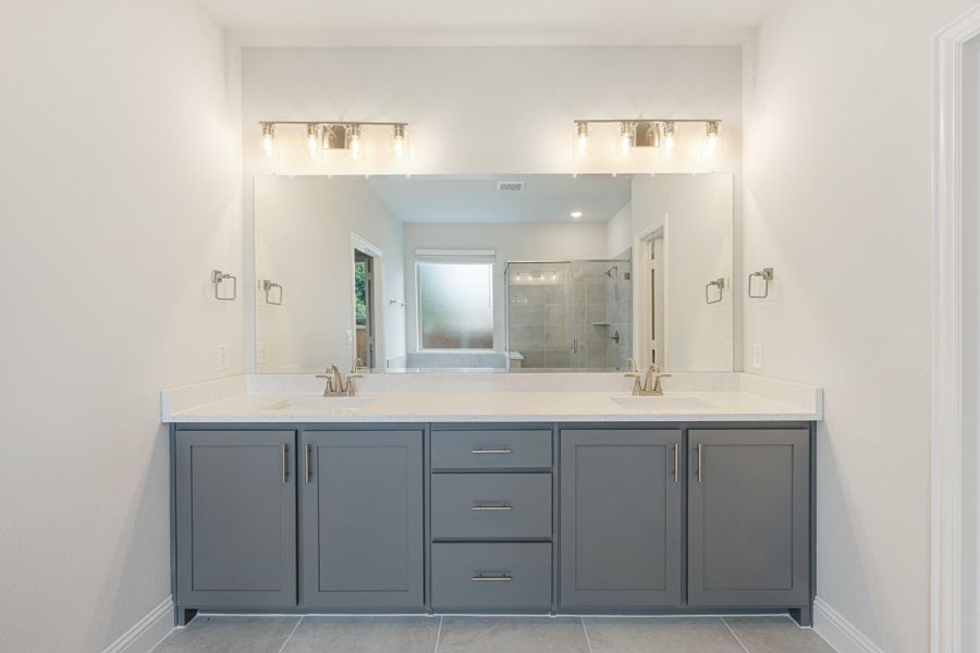 Bathroom with double vanity, gray cabinets, white countertops, and large mirror with wall sconces above Bathroom with double vanity, gray cabinets, white countertops, and large mirror with wall sconces above