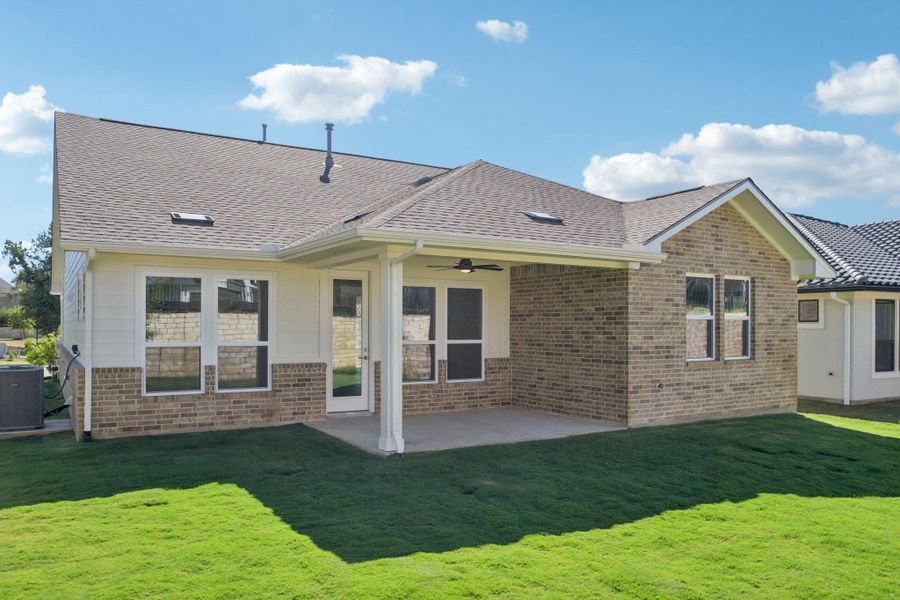 Back of house with a lawn, a patio area, a ceiling fan, and roof with shingles