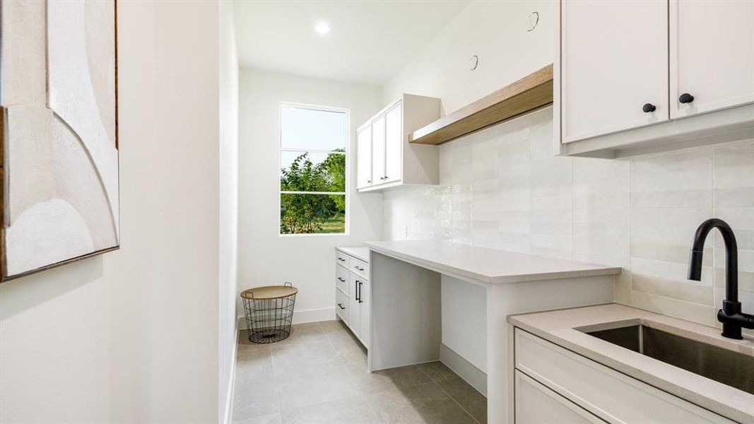 Kitchen with sink, decorative backsplash, light tile patterned floors, and white cabinetry