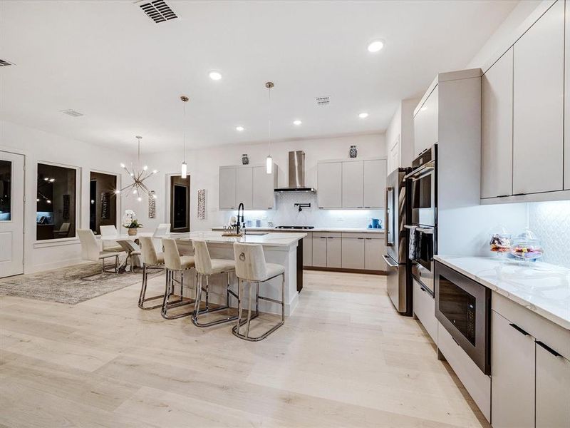 Kitchen with backsplash, modern cabinets, a breakfast bar, hanging light fixtures, and a chandelier Kitchen with backsplash, modern cabinets, a breakfast bar, hanging light fixtures, and a chandelier