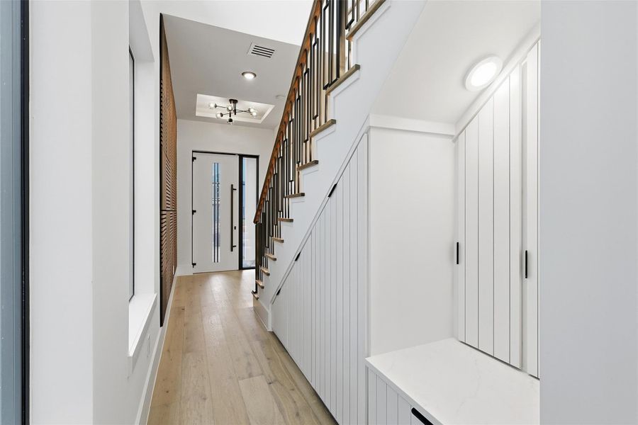 Functional custom built-ins and a seating bench are integrated beneath the staircase to maximize storage space.