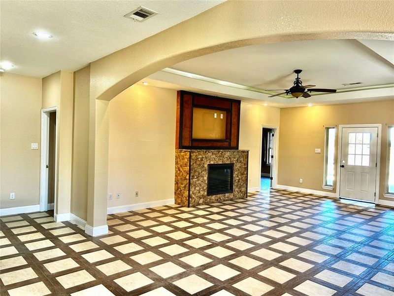 Unfurnished living room featuring ceiling fan, a textured ceiling, and a tray ceiling