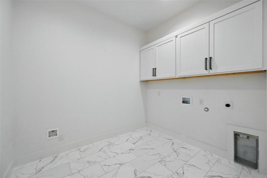 Laundry area featuring cabinet space, hookup for an electric dryer, gas dryer hookup, washer hookup, and light marble finish floors Laundry area featuring cabinet space, hookup for an electric dryer, gas dryer hookup, washer hookup, and light marble finish floors