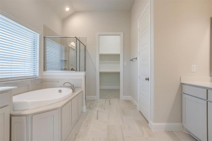 Bathroom with plus walk in shower, vaulted ceiling, tile patterned flooring, and vanity