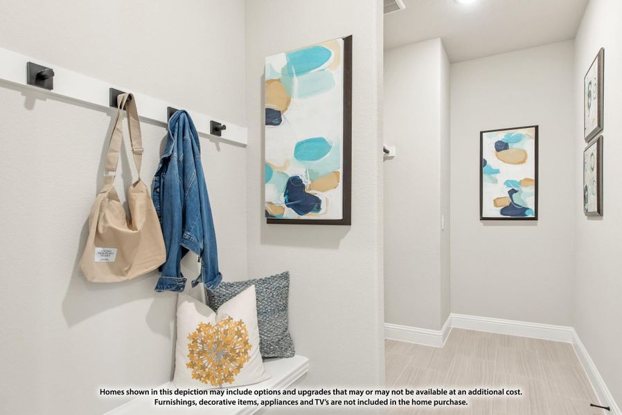 Mudroom entryway with wall-mounted coat hooks, bench with decorative pillows, and hallway with framed artwork Mudroom entryway with wall-mounted coat hooks, bench with decorative pillows, and hallway with framed artwork