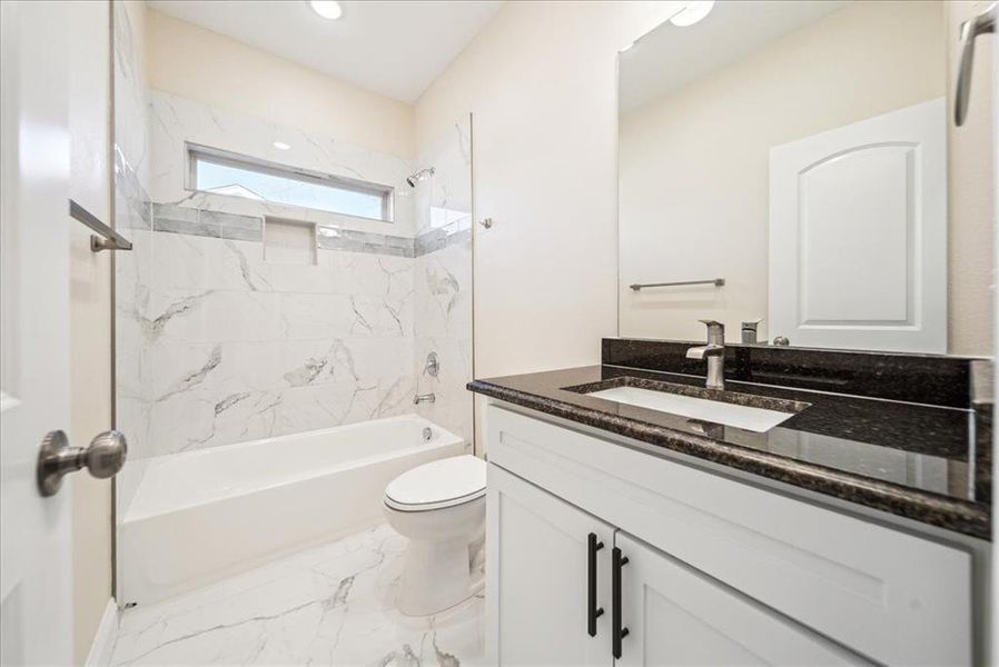 Full bathroom with vanity, tiled shower / bath combo, and toilet