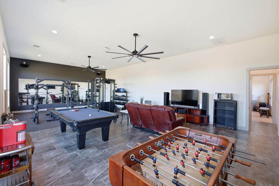 Spacious entertainment room featuring large format tile flooring, recessed lighting, and ceiling fans