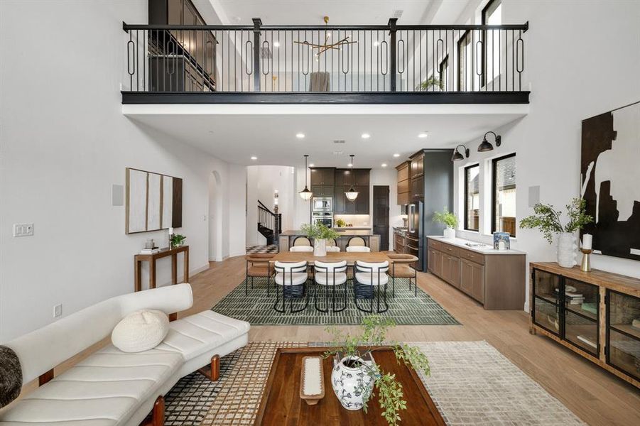 Living room with a towering ceiling, light wood finished floors, stairs, and recessed lighting Living room with a towering ceiling, light wood finished floors, stairs, and recessed lighting