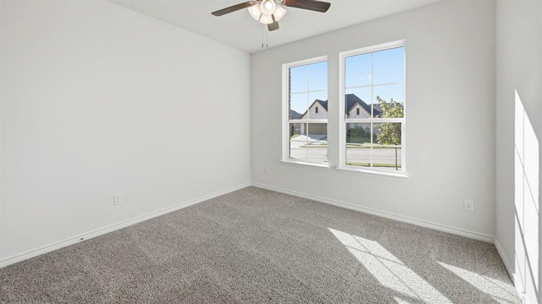 Carpeted empty room featuring baseboards and a ceiling fan