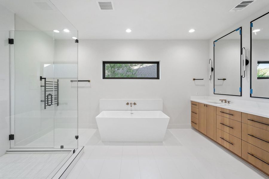 The fresh feel of the design everywhere else comes home here in the Primary Bath. The high end mirrors are seen in every bath in the house. the warm wood of the custom cabinets go well with the quartz counter top and specialty plumbing fixtures.