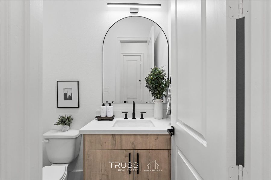 A refined half-bath features warm textures and modern fixtures, an elegant reflection of the home’s overall design ethos.